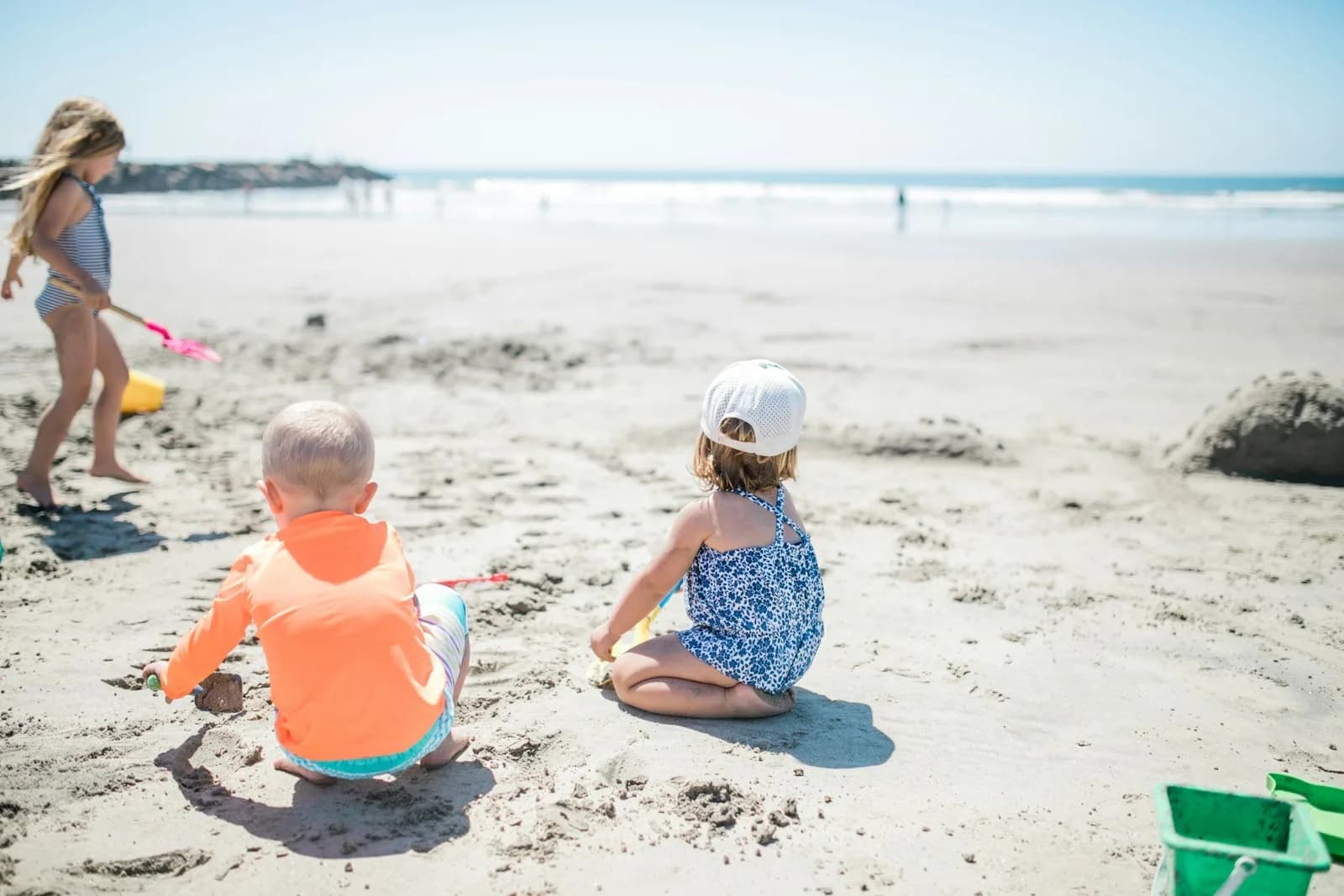 Tres niños juegan en la arena frente al mar